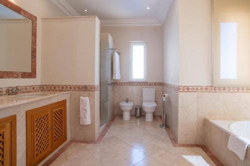 een badkamer met een bad, een wastafel en een toilet bij Palheiro Village Resort in Funchal