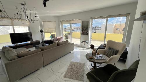 a living room with a couch and chairs and a tv at Renata's Three bedrooms Penthouse with Sea view in Il-Gżira