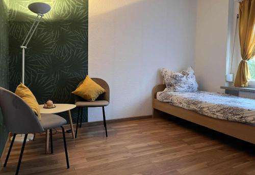Una pequeña habitación con una cama, una mesa y sillas. en Gästehaus, en Neustadt