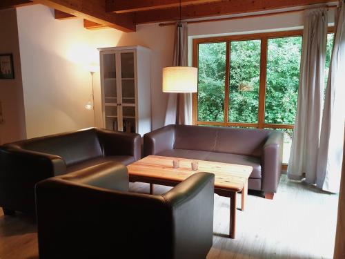 ein Wohnzimmer mit Ledersofas und einem Holztisch in der Unterkunft Natur Ferienpark 17 - Ferienhaus Typ A in Nieheim