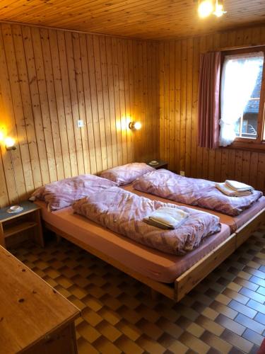 two beds in a wooden room with a window at bella Romantica in Brunig