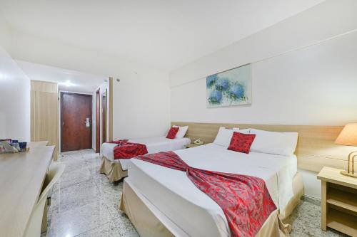 a bedroom with two beds and a table with a desk at Hotel Nacional Inn Campinas Trevo in Campinas