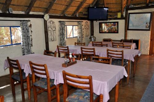 a dining room with tables and chairs and a television at Blou Windpomp Guest Lodge in Delmas