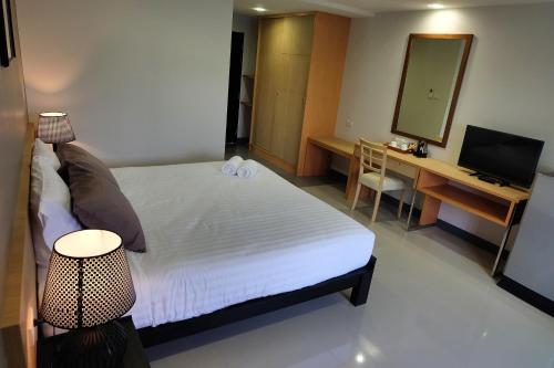 ハジャイにあるWisdom Residenceのベッドと机と鏡のある寝室