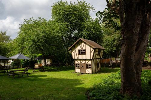 a small chicken coop in a yard next to a tree at The Poacher Inn in Upton Grey