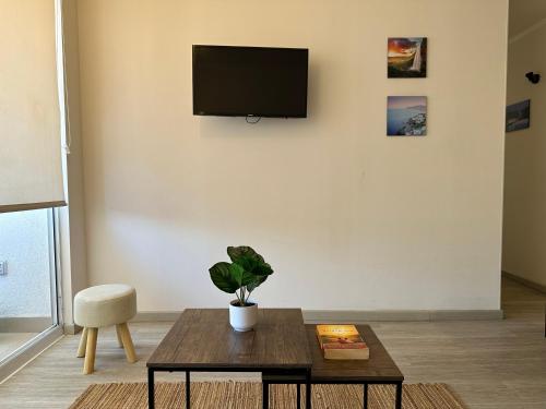 a living room with a table and a tv on a wall at Departamento nuevo a 5 min de la playa 2D 2B in La Serena