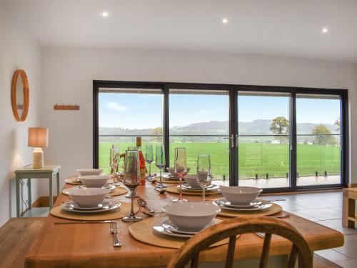a dining room table with a view of a field at Acre Luxury Lodges-Cedar Lodge in Evenjobb