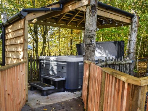 a gazebo with a trash can and a tree at Acre Luxury Lodges-Cedar Lodge in Evenjobb