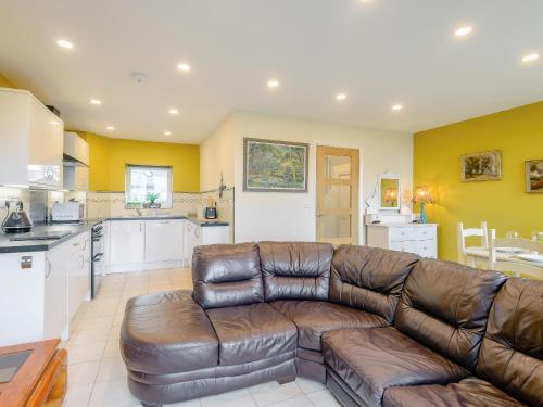 a living room with a leather couch and a kitchen at Dutch Barn Two - Uk12873 in Brynkir