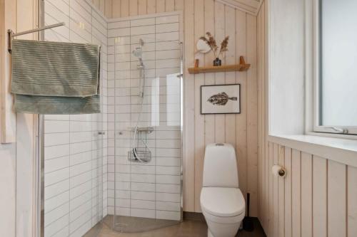 a white bathroom with a toilet and a shower at Snug In Snogebæk A Modern Cozy Summer House in Neksø