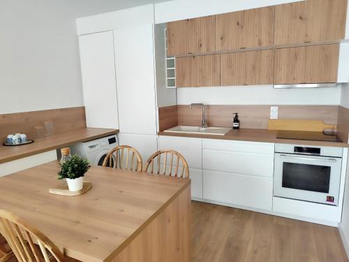 une cuisine avec des armoires blanches et une table en bois dans l'établissement Appartement cosy en centre-ville, à Calais