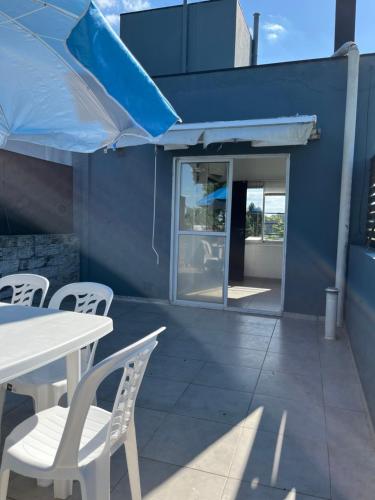 a patio with a white table and white chairs at Orillas del Sol Triplex in Chascomús