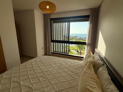 a bedroom with a bed and a large window at Sea View Apartment & Swimming Pool in Sidi Bouqnadel