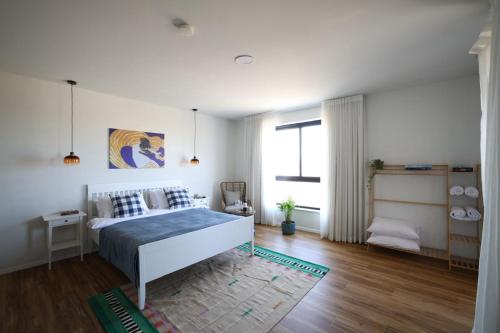a white bedroom with a bed and a window at וילה מעגל השמש in Poriyya Illit