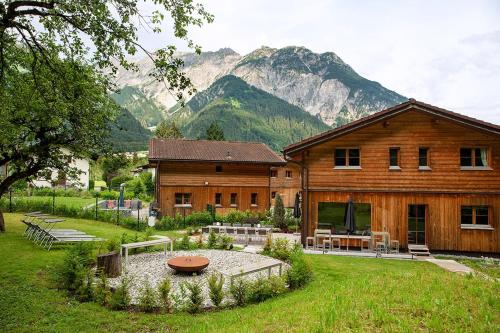 a large wooden house with mountains in the background at Chalet Auszeit Montafon in Bartholomäberg