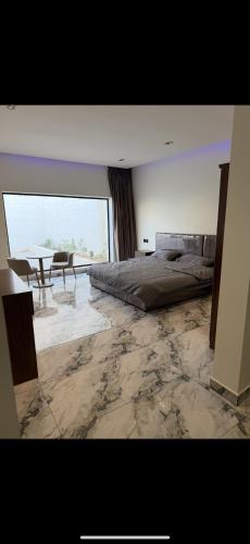 Un dormitorio con una cama y una mesa dentro. en شاليه داله العماريه2 بالكامل لك وأجواء ممتعه, en Al ‘Ammārīyah