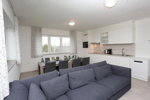 a living room with a blue couch and a kitchen at Het Polderzicht in Mellet