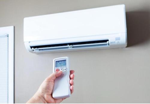 a person holding a remote control in front of a air conditioner at UIM Mediterraneo Isabel 10 Wifi in Puerto de Sagunto