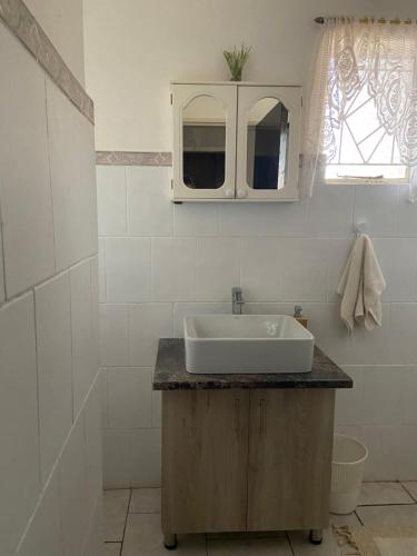 a white bathroom with a sink and a mirror at Highway Haven in Stilfontein