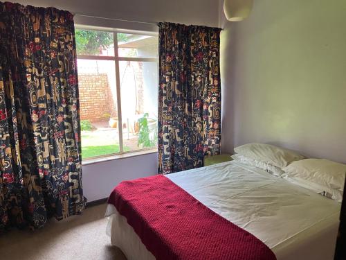 a bedroom with a bed and a window with curtains at Highway Haven in Stilfontein