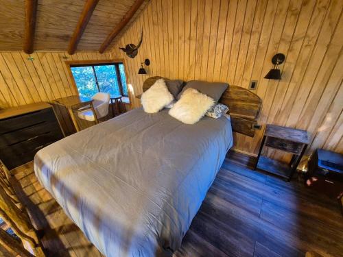 a bedroom with a bed in a room with wooden walls at Casa de árbol Quillón in Quillón