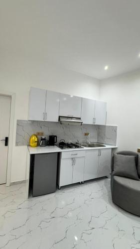 una cucina con mobili bianchi e un divano in una stanza di Amour Homes 2 a Quba