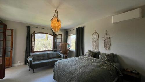 ein Schlafzimmer mit einem Bett, einer Couch und einem Kronleuchter in der Unterkunft Provencal Villa With Pool And Panoramic Views in La Gaude