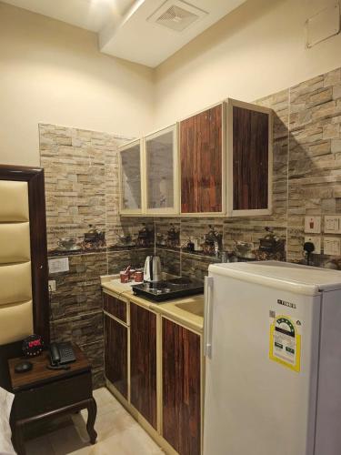 a kitchen with wooden cabinets and a white refrigerator at Roaa Apartments in Al Qunfudhah