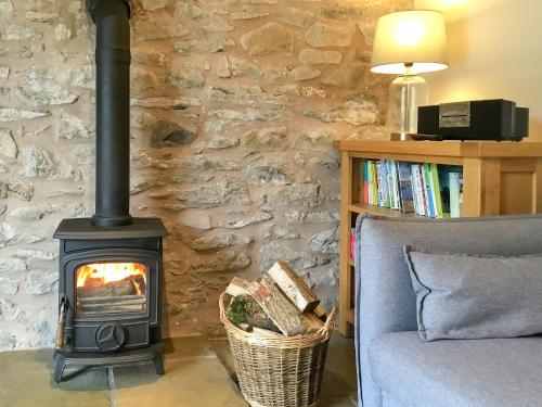 einen Holzofen im Wohnzimmer mit Sofa in der Unterkunft Crabapple Cottage in Llanyblodwel