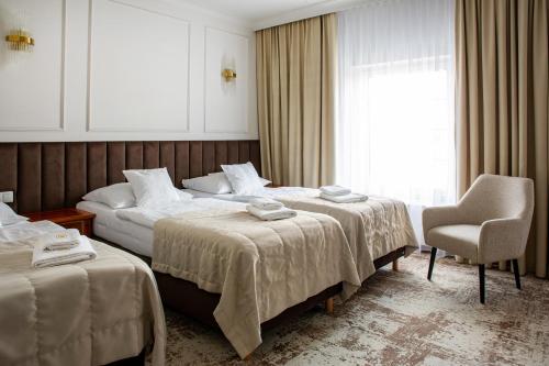 a hotel room with two beds and a chair at Hotel Piast in Opole