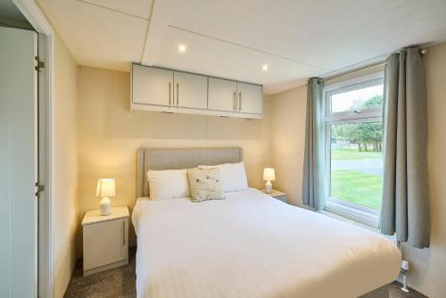 a bedroom with a white bed and a window at Nightingale Lodge with Hot Tub in Barmby on the Moor