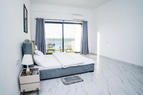 a bedroom with a bed and a large window at Sweet Apartment in Tanga