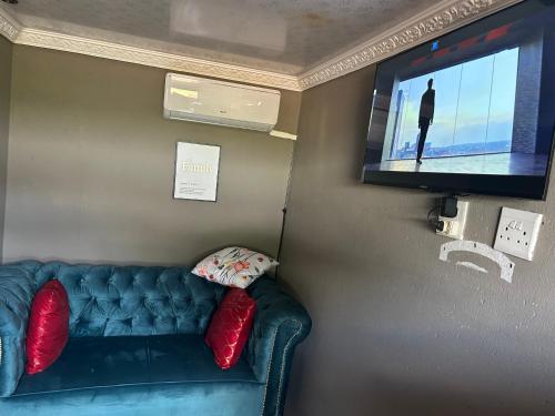een woonkamer met een bank en een flatscreen-tv bij Lake boutique hotel empire in Thohoyandou