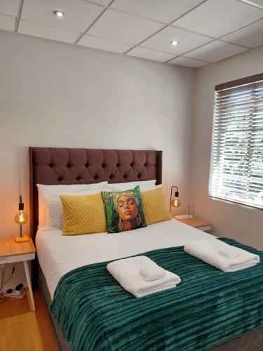 a bedroom with a large bed with two towels on it at The Skinny Expat - Paarl - Self Catering Apartment in Paarl