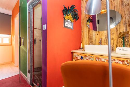 a bathroom with an orange wall and a mirror at Casa da Almoinha in Unhais da Serra