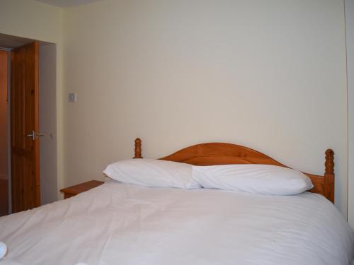a bed with a wooden headboard and two white pillows at Taigh Na Beadan in Valtos
