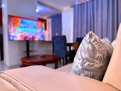 a pillow on the back of a couch with a tv at CHS Vacation Stays Limited in Kampala