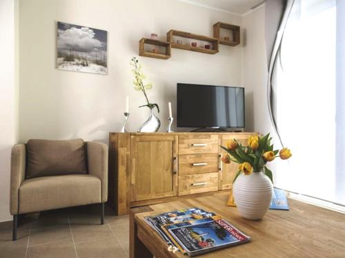 a living room with a tv and a chair and a table at DUENENZEIT App Nr 5 max 4 Pers in Dierhagen