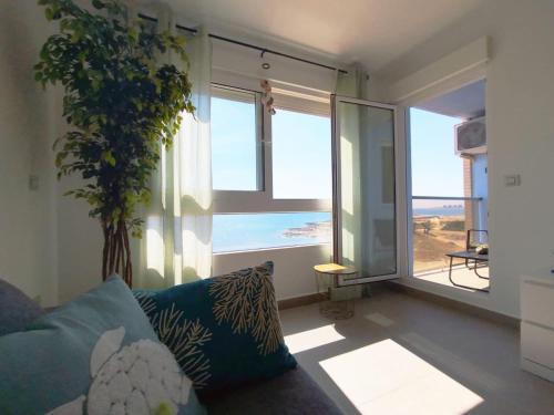 een woonkamer met een bank en een groot raam bij El mar de la tranquilidad in La Manga del Mar Menor