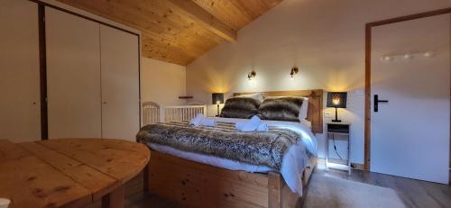 a bedroom with a large bed and a wooden table at Chalet Mugnier in Samoëns