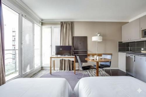 a bedroom with a bed and a table and a kitchen at GuestReady - Studio cosy près du métro in Issy-les-Moulineaux