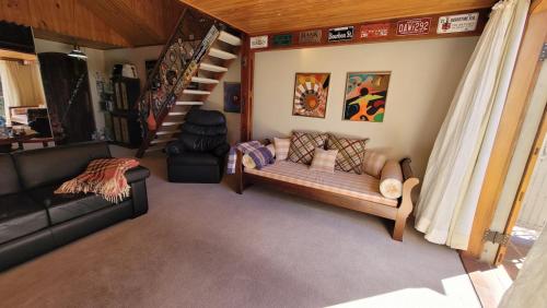 ein Wohnzimmer mit einer Couch und einer Treppe in der Unterkunft Tranquility and Nature - 8 minutes from downtown Capivari in Campos do Jordão