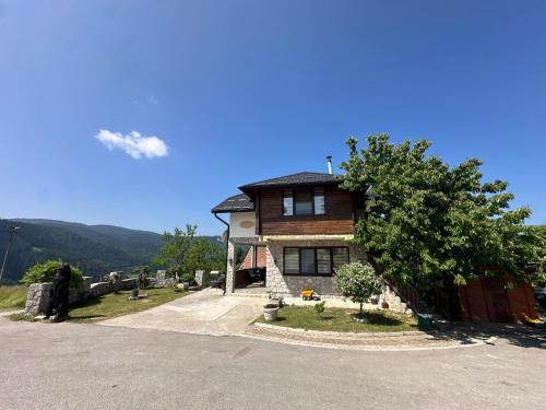 a house on top of a hill with a tree at Apartmani Dunja Zlatar in Nova Varoš