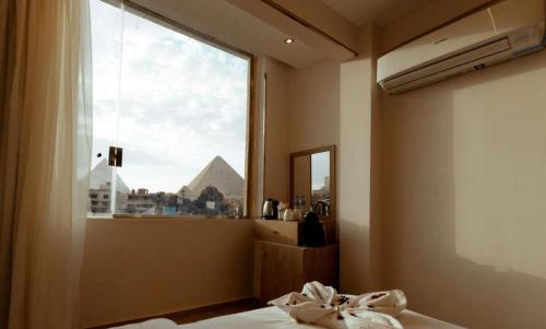 1 dormitorio con ventana y vistas a las pirámides en Honey Pyramids Hotel, en El Cairo