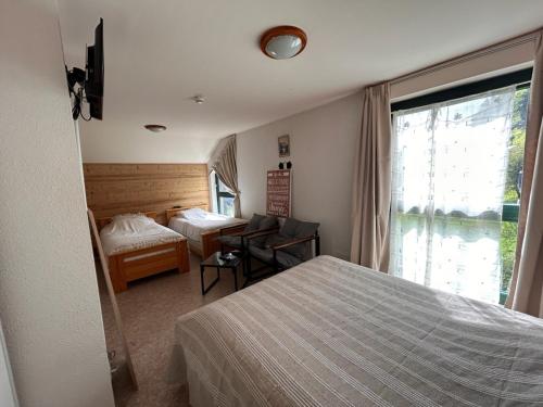 a hotel room with two beds and a window at Auberge le bois du cornet in La Forclaz
