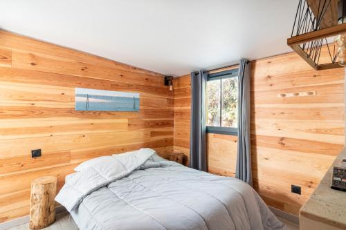 - une chambre avec des murs en bois et un lit avec une fenêtre dans l'établissement Lou Cabanot 640 portes du Bassin, à Le Barp