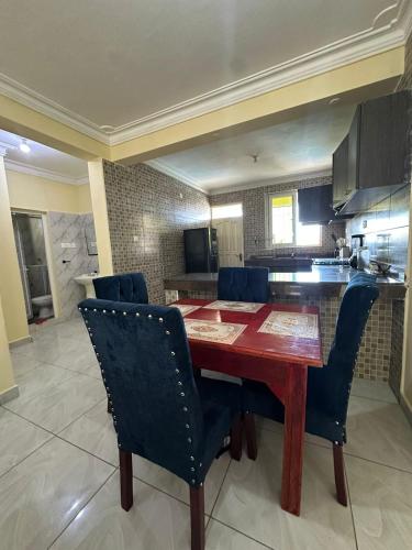 cocina con mesa de madera y sillas azules en Tamara Apartments, en Mombasa