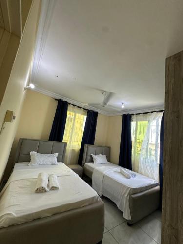 Dos camas en una habitación pequeña con ventanas. en Tamara Apartments, en Mombasa