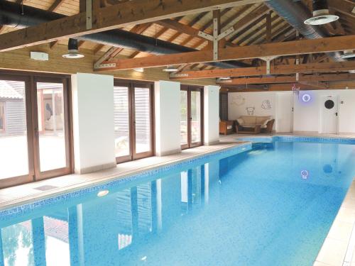 a large swimming pool in a building with windows at Burfields Barn in Rickinghall