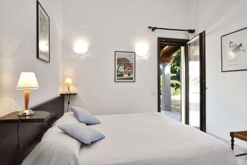 een witte slaapkamer met een bed en een lamp bij Villa Rosamar in Monte Nai